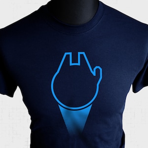 Può includere: Una t-shirt blu navy con un contorno blu della nave spaziale Millennium Falcon di Star Wars.