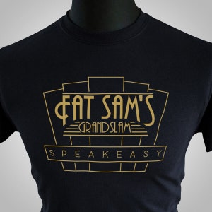 May include: Black t-shirt with a gold graphic design that says "Fat Sam's Grand Slam Speakeasy".