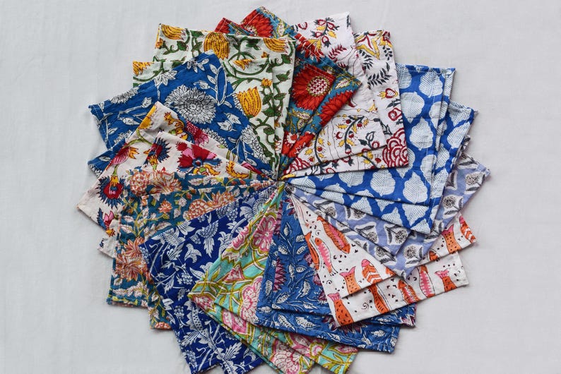 May include: A collection of colorful fabric napkins with floral and geometric patterns. The napkins are arranged in a circle, with the edges of each napkin overlapping the next.