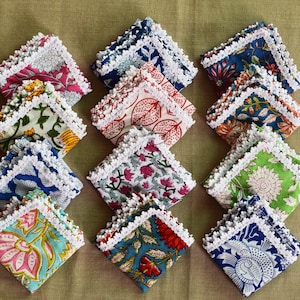 May include: A set of 10 colorful fabric napkins with white lace trim. Each napkin features a different floral print.