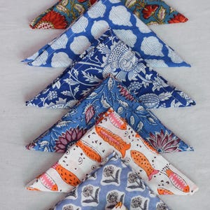 May include: A set of eight triangular fabric napkins with various colorful floral and geometric patterns. The napkins are made of cotton and are perfect for adding a touch of elegance to any table setting.