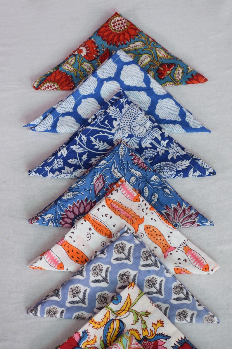 May include: A set of eight triangular fabric napkins with various colorful floral and geometric patterns. The napkins are made of cotton and are perfect for adding a touch of elegance to any table setting.
