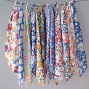 May include: A set of ten colorful cotton tea towels with floral patterns in shades of blue, pink, yellow, and red. The towels are hanging on a string and are ready to be used.