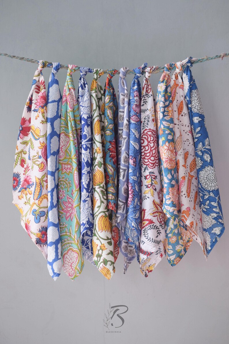 May include: A set of ten colorful cotton tea towels with floral patterns in shades of blue, pink, yellow, and red. The towels are hanging on a string and are ready to be used.