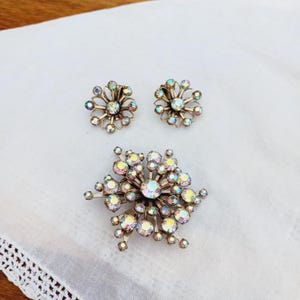 K&ouml;nnte beinhalten: Ein Set aus schimmerndem Strassschmuck mit einer gro&szlig;en Brosche in Form einer Schneeflocke und einem Paar passender Ohrringe.