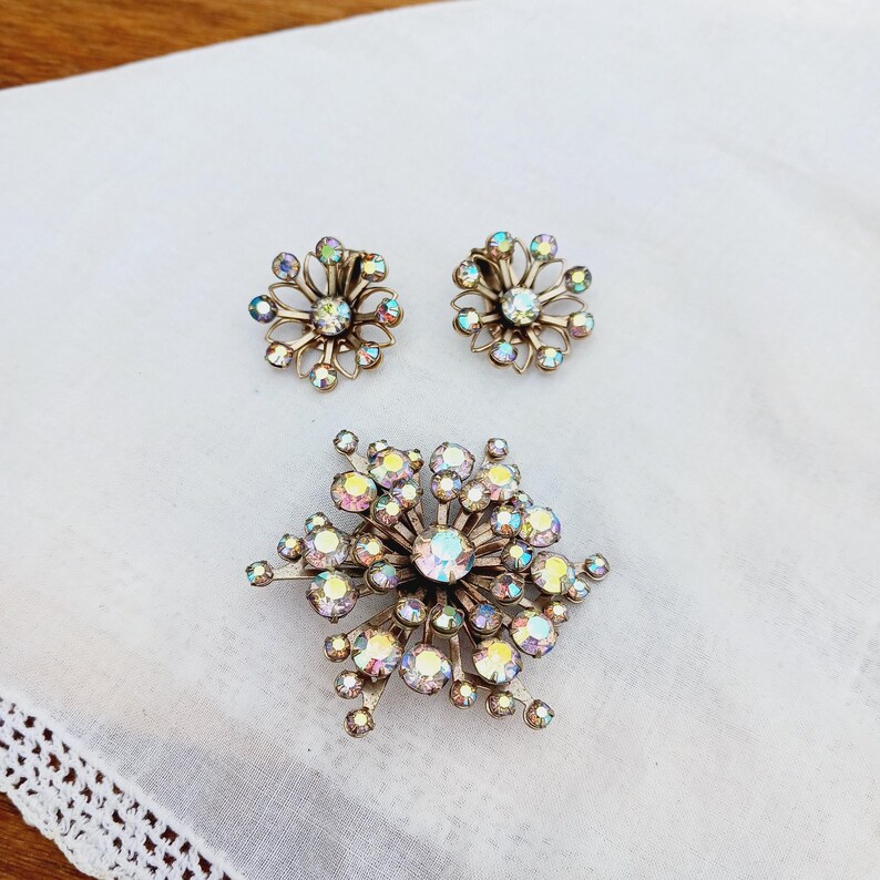 K&ouml;nnte beinhalten: Ein Set aus schimmerndem Strassschmuck mit einer gro&szlig;en Brosche in Form einer Schneeflocke und einem Paar passender Ohrringe.