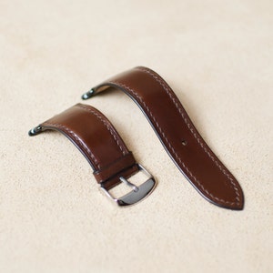 May include: Two brown leather watch straps with stitching detail. One strap has a silver buckle.
