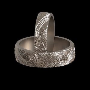May include: Two silver wedding bands with a swirling, textured design.