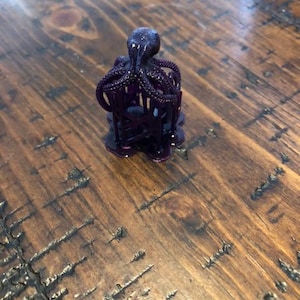 May include: A small, purple 3D printed octopus figurine with eight tentacles.