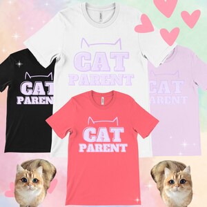 May include: A collection of t-shirts in black, white, pink, and coral, each featuring the text "CAT PARENT" in a light purple font with a cat silhouette above the text. The image also includes two cats and pink heart shapes.