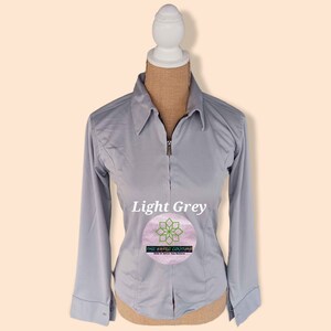 May include: Light grey long-sleeve collared shirt with a zipper closure. The shirt is on a mannequin and has the text "The Aesthetic Couture" on a pink circle.