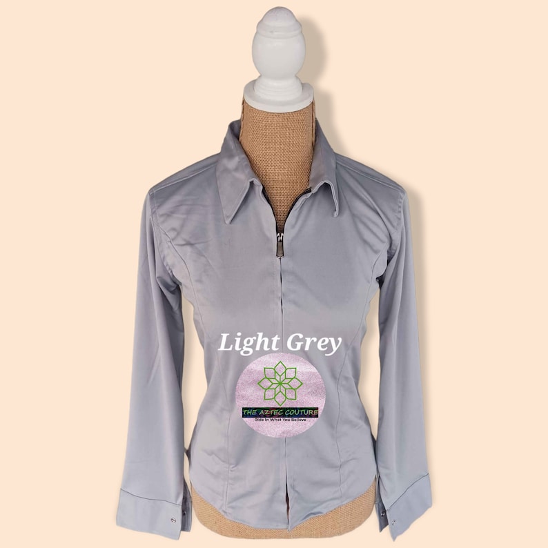 May include: Light grey long-sleeve collared shirt with a zipper closure. The shirt is on a mannequin and has the text "The Aesthetic Couture" on a pink circle.