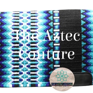 Op de afbeelding: Een rechthoekig paardrijzadeldek met een levendig Azteeks ontwerp. Het dek heeft een patroon van turquoise, witte en zwarte geometrische vormen, omlijst door een diepblauwe rand. De tekst "The Aztec Couture" is zichtbaar.