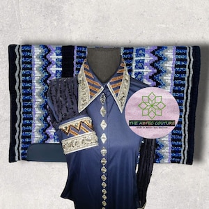 May include: A navy blue shirt with a silver and brown embellished collar and cuffs. The shirt has a diamond pattern and is paired with a blue and purple horse blanket with a white and silver geometric pattern. The blanket has the text "THE AZTEC COUTURE" and "Ride in What You Believe".