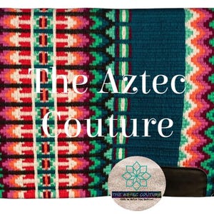 Op de afbeelding: Een turquoise zadeldek met een Azteeks ontwerp. Het heeft een centrale verticale streep en randen met geometrische patronen in rood, roze, groen en wit. De tekst "The Aztec Couture" staat op het zadeldek.