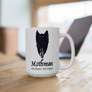 May include: White ceramic coffee mug with a black silhouette of the Mothman, a cryptid with large eyes and wings, and the text "Mothman Point Pleasant West Virginia".