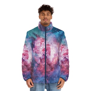 May include: A puffer jacket featuring a vibrant galaxy print in shades of blue, pink, and purple. The jacket has a high collar, a full-length zipper, and a dark blue trim. The jacket is worn by a person in blue jeans.