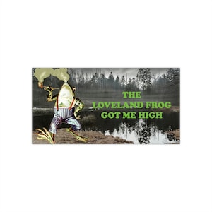Könnte beinhalten: Ein Cartoon-Frosch in einem blau-weiß gestreiften Outfit raucht eine Pfeife in einem sumpfigen Wald. Der Text "THE LOVELAND FROG GOT ME HIGH" ist in grünen Buchstaben geschrieben.