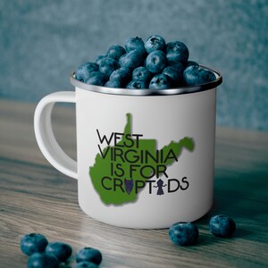 May include: White enamel camping mug with a green outline of the state of West Virginia and the text "West Virginia is for Cryptids".