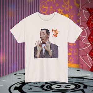 May include: Off-white t-shirt featuring a graphic of a man with his hands up and the text "Fuck This Shit" in red. The man is wearing a suit and bow tie. The shirt has short sleeves and a crew neck.
