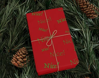 May include: A wrapped gift with red paper and green text that says "Nice!" repeatedly. The gift is tied with twine and rests on a bed of green pine needles and pine cones, creating a festive holiday scene.