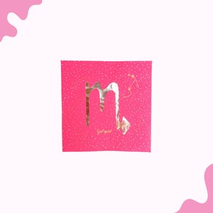 May include: A hot pink square card featuring a gold foil Scorpio symbol and constellation details. The word "Scorpio" is written in gold script below the symbol. The background has a subtle speckled pattern.