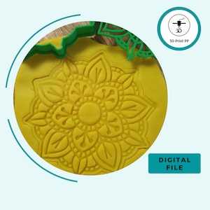 Op de afbeelding: Een gele 3D-geprinte mandala koekjesvormer met een gedetailleerd ontwerp. De vormer wordt getoond ingedrukt in gele modelleerklei. De afbeelding bevat ook de tekst "3D Print PP" en "DIGITAL FILE".
