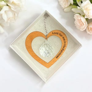 May include: A wooden heart-shaped ornament with a crystal hanging from it. The ornament has the text "Look for me in the rainbows" engraved on it.
