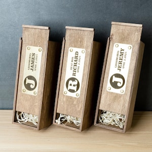 May include: Three wooden boxes with lids, each with a brass plaque engraved with a name, title, and date. The boxes are filled with shredded paper.