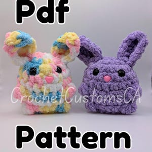 以下が含まれることがあります： 2匹のウサギのぬいぐるみを編むためのPDFパターン。1匹のウサギはピンク、ブルー、イエロー、ホワイトの糸でマルチカラー。もう1匹のウサギはパープル。両方のウサギは黒い目とピンクの鼻をしています。