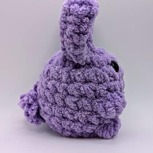 May include: A plush purple crocheted bunny with a long ear and a black button eye.