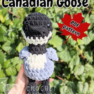 May include: A handmade crochet Canadian Goose plushie in black, white, and blue. The goose has a black head, neck, and feet, with a white and black patterned face and a blue body. The text "Canadian Goose" and "PDF pattern" are visible.