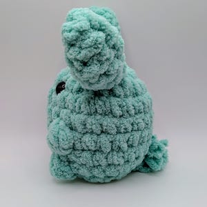 May include: A crocheted plush toy in the shape of a bunny, with a light blue color and black eyes.