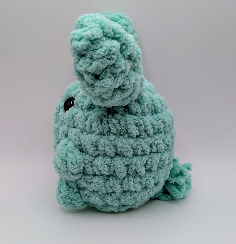 May include: A crocheted plush toy in the shape of a bunny, with a light blue color and black eyes.
