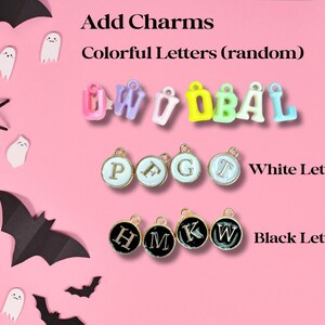 May include: Assortment of colorful letter charms for jewelry making. The charms are in various colors, including pink, blue, yellow, and green. There are also white and black letter charms.