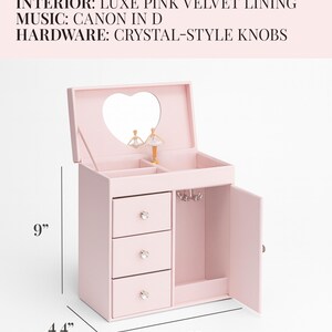May include: A soft pink jewelry box with a smooth PU leather finish, pink velvet interior, and crystal-style knobs. It features a heart-shaped mirror, a rotating dancer, three drawers, and a side compartment. Dimensions are 9 inches by 8 inches by 4.4 inches.