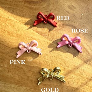 May include: Available bow colors: red, rose, pink, and gold. The bows are made of a shiny material and have a simple design.
