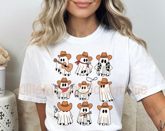 May include: White t-shirt with a graphic of nine cartoon ghosts wearing cowboy hats and holding various props, including a guitar, lasso, and pistols.