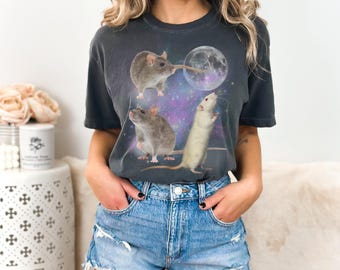 May include: A dark gray t-shirt with a graphic of three rats reaching for a moon in a galaxy print. The rats are gray and white.