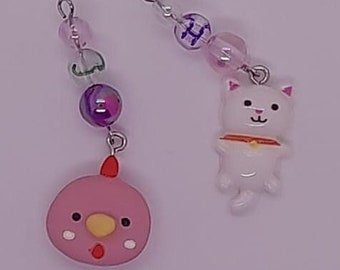 Puede incluir: Dos collares con dijes de cuentas rosadas y moradas. Un dije es un pollo rosa y el otro es un gato blanco.