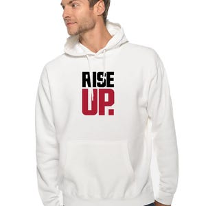 May include: White hooded sweatshirt with the words "RISE UP" printed in black and red on the front.