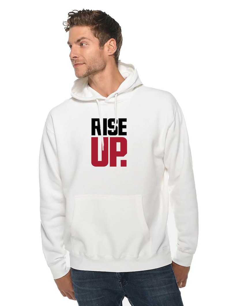 May include: White hooded sweatshirt with the words "RISE UP" printed in black and red on the front.