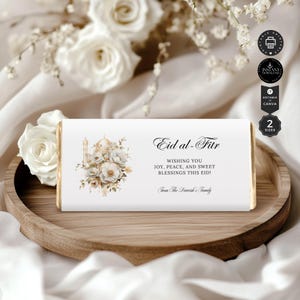 Könnte beinhalten: Ein weißer Schokoladenriegel-Wrapper mit goldener Umrandung und einem floralen Design. Der Wrapper trägt den Text "Eid al-Fitr" und "Wishing you joy, peace, and sweet blessings this Eid!"  Der Wrapper trägt auch den Text "From The Darvesh's Family".