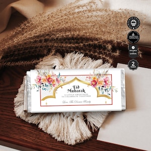 May include: A white chocolate bar wrapper with a gold and red floral design. The wrapper has the text "Eid Mubarak" and "A little sweetness to celebrate together." It also includes the text "Love, The Darwis Family".