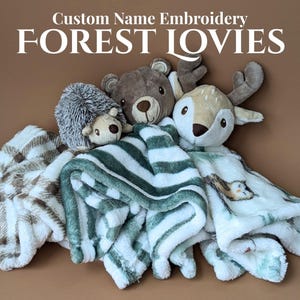 May include: A collection of plush animal lovies, including a hedgehog, bear, and deer, atop soft blankets. The blankets feature patterns like plaid and stripes. Text at the top reads "Custom Name Embroidery FOREST LOVIES."