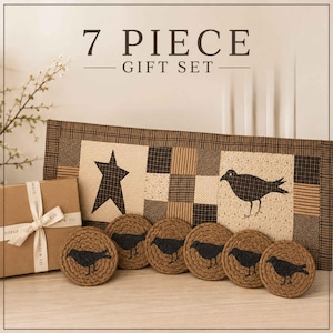 May include: A 7 piece gift set featuring a rectangular fabric table runner with a black and tan checkered star and crow pattern, a brown cardboard gift box tied with a branded ribbon, and six round woven coasters with black crow silhouettes.