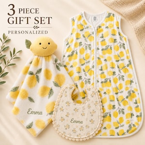 A 3-piece gift set featuring a yellow and green baby outfit, a yellow and green bib, and a yellow and green towel with a lemon pattern.