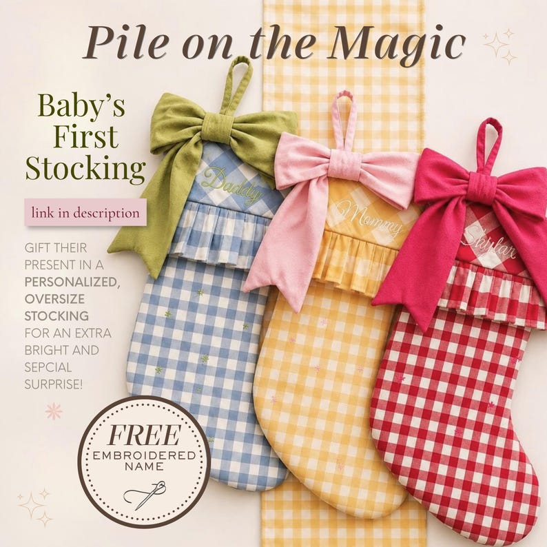 The image is an advertisement for a "Baby's First Stocking" that features three colorful, embroidered stockings with bows. The text on the image includes "Pile on the Magic" and "Baby's First Stocking" along with a description of the product, which is a personalized, oversized stocking for an extra bright and special surprise. The ad also includes a free embroidered name and a free embroidery kit.