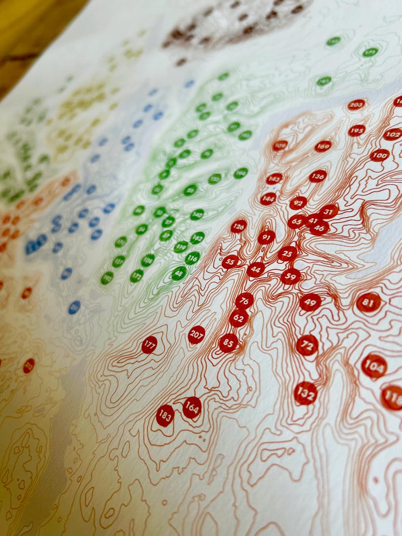 Puede incluir: Una impresi&oacute;n detallada de un mapa topogr&aacute;fico con l&iacute;neas de contorno en tonos naranja y marr&oacute;n. Puntos de colores en verde, azul y rojo est&aacute;n dispersos por el mapa, cada uno con un n&uacute;mero. El mapa est&aacute; impreso en papel color crema.