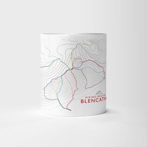 Puede incluir: Taza de cerámica blanca con un diseño de mapa colorido que muestra rutas de senderismo. La taza tiene un estilo minimalista con el texto "Hiking Routes Blencathra" en rojo. El diseño del mapa incluye líneas de varios colores.